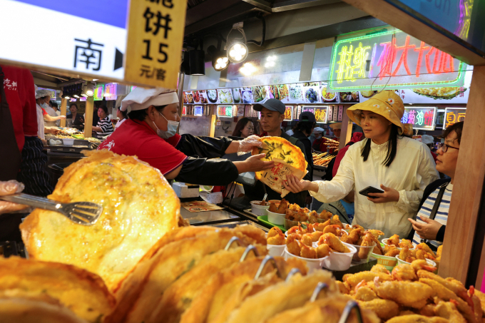 Người dân mua đồ tại một khu chợ ở Thượng Hải tháng 5/2025. Ảnh: Reuters