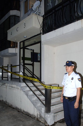 A police officer stands guard at the main entrance of the apartment block in Ulsan where the arson occurred in September 2006.