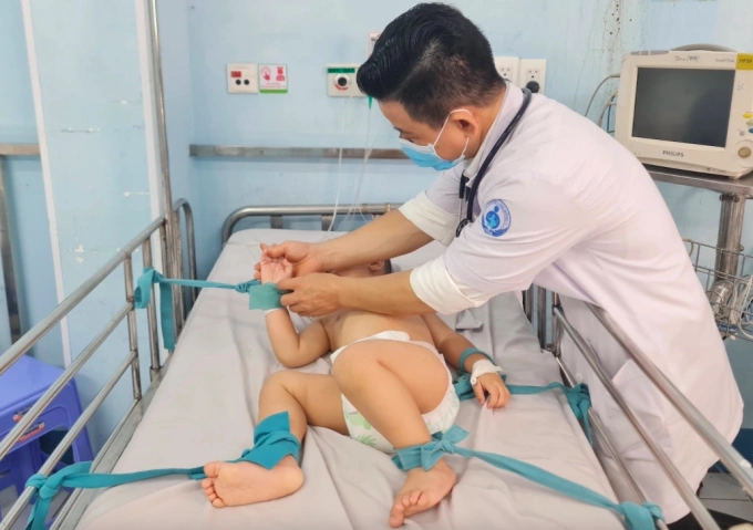 Trẻ tay chân miệng nặng điều trị tại bệnh viện Nhi đồng 1, được cố định tay chân vào giường để tránh kích thích. Ảnh:Lê Phương