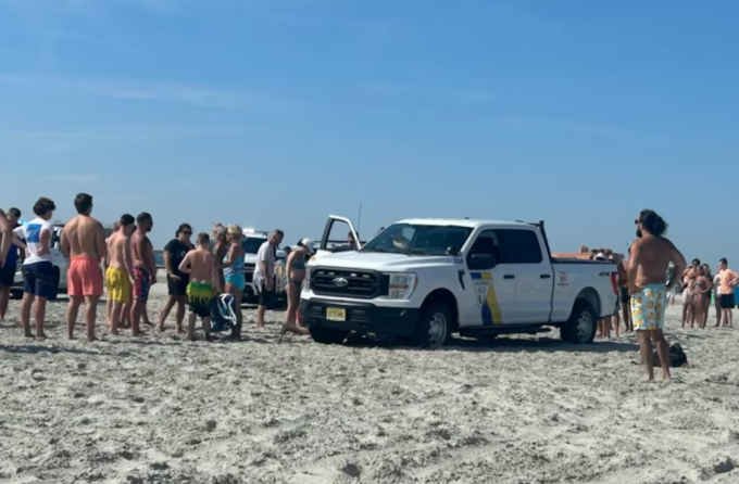 Những người chứng kiến đã giúp nâng chiếc xe bán tải của cảnh sát Wildwood lên để giải cứu người phụ nữ bị xe cán qua khi đang nằm trên bãi biển vào ngày 28/8/2024. Ảnh: NJ