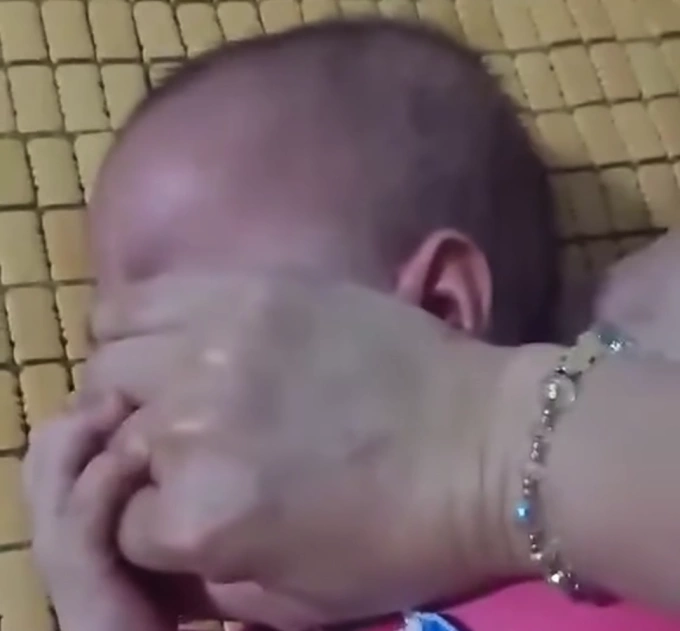Người mẹ nhiều lần bịt mặt con nhiều lần khiến bé gái khóc lóc, dấu hiệu nghẹt thở. Ảnh: Chụp video